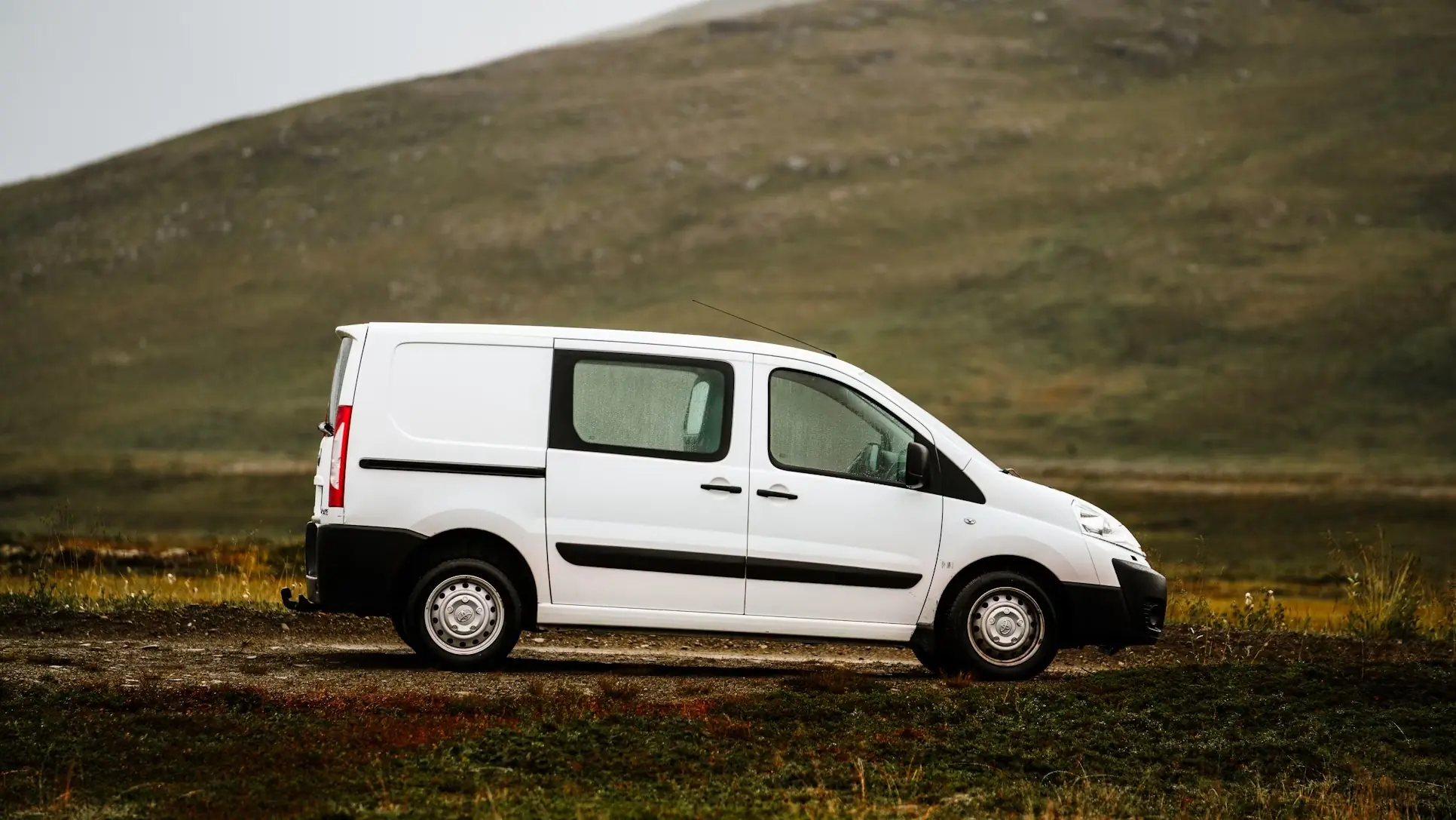 Weißer Lieferwagen vor einer Berglandschaft